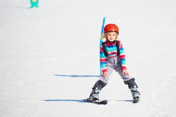child girl skiing in mountains. active kid with safety helmet and goggles. ski race for young childr