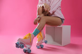 Young woman with retro roller skates on color background, closeup. Space for text