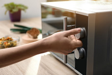 Young Woman Adjusting Modern Microwave Oven In Kitchen, Closeup