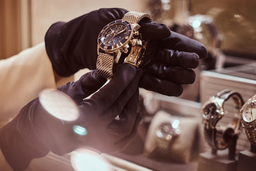 Close-up of the seller's hands in gloves shows the exclusive men's watch from the new collection in the luxury jewelry store