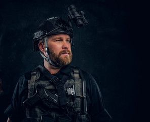 Wall Mural - Portrait of a special forces soldier wearing body armor and helmet with a night vision. Studio photo against a dark textured wall