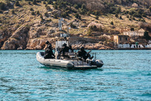Group Of Military Soldiers Or SWAT In Black Uniform, Masks And Weapons On Special Navy Boat On Sea