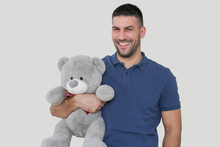 Portrait of a young handsome man holding a big teddy bear