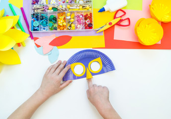 A child makes a bird mask out of paper. Master class crafts. Tropical Parrot.