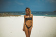 © South House Studio - thin adult girl in black bikini and sunglasses walks along the white sand beach,