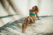 © South House Studio - sexy slim tanned blonde in a blue swimwear isolated on white beach sand,