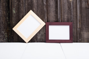 brown painted and natural wood picture frame, white table, old wooden wall