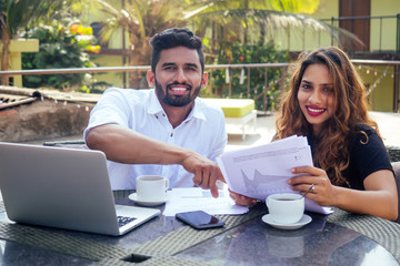 Portrait of happy businesswoman and businessman at summer tropical cafe.freelance and remote work.woman and Arab man couple in love work together on the shore of india ocean