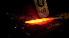 MACRO: Red Hot Piece Of Metal Is Held By Tongs And Struck By A Big Hammer.