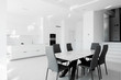 © steftach - Luxurious modern dining room with white table, black chairs and white modern kitchen.  Minimalistic style.