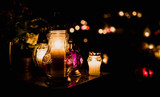 Fototapeta  - The cemetery, candles burning in lanterns at night during All Saints Day, bokeh of light candle.
