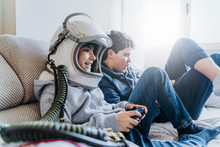 Two Kids Lying On Couch And Playing With A Video Game Console At Home