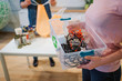 © estradaanton - Recycling concept. Mixed electronic waste in plastic contaner close-up. Responsible woman is protecting environment while sorting the waste at home