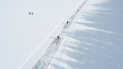 Wall Mural - Aerial view of frozen lake People are skating on the ice.