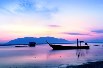 The first  light of day..Seascape at fishermen village with twilight water reflection long tail boat and floating basket .