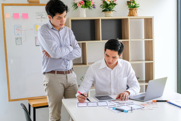 Wall Mural - two young asian man designer website applications consulting and planning work together. job trainin