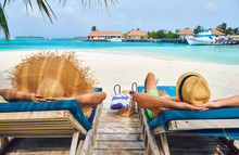 Couple At Beach On Wooden Sun Bed Loungers