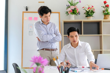 Wall Mural - two young asian man designer website applications consulting and planning work together. job trainin
