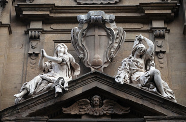 Poster - Statues of Hope and Poverty seated either side of the arms of the Theatine order over the central door on the facade of Santi Michele e Gaetano church in Florence, Italy