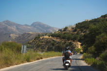 Travelers Couple On Scooter Riding A Mountain Road. Crete Island, Greece