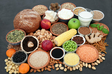 Large vegan health food collection on slate background. Super foods high in antioxidants, protein, vitamins, anthocyanins, minerals and dietary fibre.