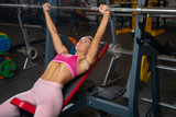 Young woman lying on bench with barbell