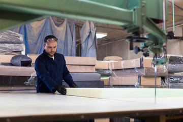 Wall Mural - Young man in a furniture factory is measuring the foam for the sofa.