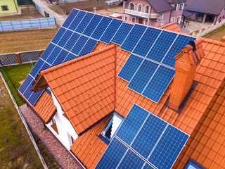 Aerial top view of new modern residential house cottage with blue shiny solar photo voltaic panels system on roof. Renewable ecological green energy production concept.