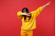© ViDi Studio - Portrait of young woman in yellow fur sweater with lowered head showing dab dance gesture isolated on bright red background in studio. People sincere emotions, lifestyle concept. Mock up copy space.