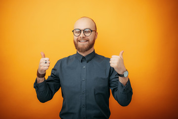 Handsome business man wearing glasses over isolated background success sign doing positive gesture with hand, thumbs up smiling and happy. Looking at the camera