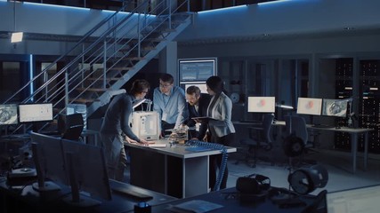 Diverse Team of Electronics Development Engineers Standing at the Desk with 3D Printer and PCB Motherboards. Specialists Collectively Working on Modern Industrial Design, Using Latest Tablet Devices