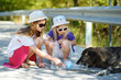 © MNStudio - Thirsty black stray dog drinking water from the plastic bottle on hot summer day. Two kids giving cool water to thirsty dog.