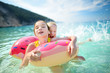 © MNStudio - Cute young sisters floating on toy ring at Myrtos beach, the most famous and beautiful beach of Kefalonia, a large coast with turqoise water and white coarse sand.
