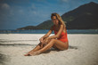 © South House Studio - pretty blonde in carrot bikini posing on white sand beach, holding arm on knees