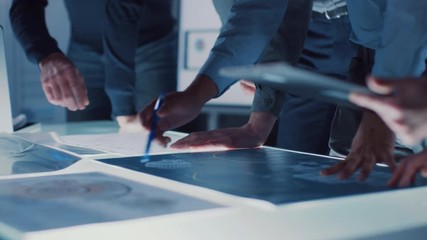 Poster - Engineer, Scientists and Developers Gathered Around Illuminated Conference Table in Technology Research Center, Talking, Finding Solution and Analysing Industrial Engine Design. Close-up Hands Shot 