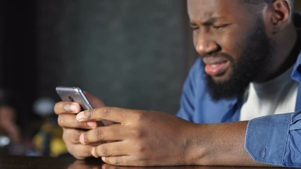Frustrated man reading rejection message sitting in pub, problems with job