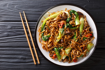 Asian vegetarian food udon noodles with baby bok choy, shiitake mushrooms, sesame and pepper close-up on a plate. horizontal top view