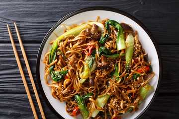 Chinese udon noodles with bok choy, shiitake and pepper close-up on a plate. Horizontal top view