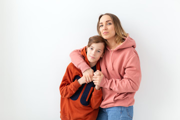 Mothers day, children and family concept - teen boy hugging his mom on white background