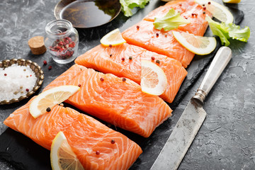 Wall Mural - Raw salmon fillet and ingredients for cooking on a dark background.