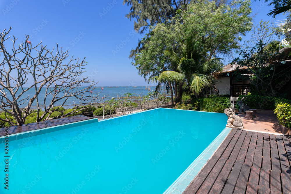 Swimming pool  blue water and tropical garden with sea view background - obrazy, fototapety, plakaty 