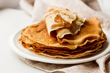 Staple of wheat golden yeast pancakes or crepes in a white plate closeup