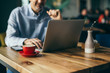© cherryandbees - closeup of coffee in red mug in cafeteria. blurred man using laptop in background