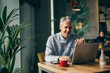 © cherryandbees - man sitting table in cafe bar and using laptop. drinking coffee.