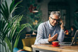 © cherryandbees - mature gray haired businessman talking on the smartphone in cafe bar