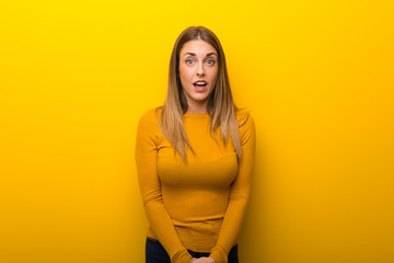 Young woman on yellow background with surprise and shocked facial expression