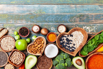 Wall Mural - Healthy food background from fruits, vegetables, cereal, nuts and superfood. Dietary and balanced vegetarian eating products on kitchen table top view.