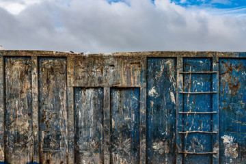 Wall Mural - close-up of a old grungy weathered industrial  dumpster, cloudy sky background