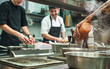 © Friends Stock - Professional team. Cheerful young cooks preparing food together in a restaurant kitchen