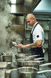 © Friends Stock - Focused on a process. Side view of handsome and young chef cooking homemade italian pasta in a restaurant kitchen